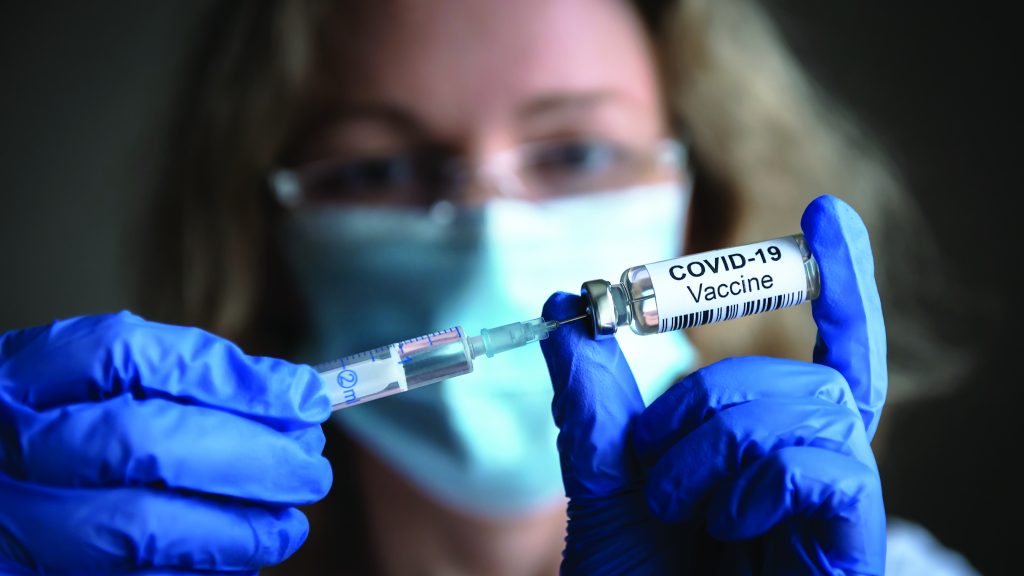 COVID-19 vaccine in researcher hands, female doctor holds syringe and bottle with vaccine for coronavirus cure. Concept of corona virus treatment, injection, shot and clinical trial during pandemic.