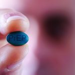 closeup of a young caucasian man with a simulated PrEP pill in his hand