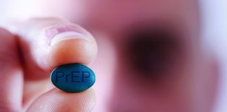 closeup of a young caucasian man with a simulated PrEP pill in his hand