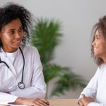 Black Nurse Practitioner With Patient