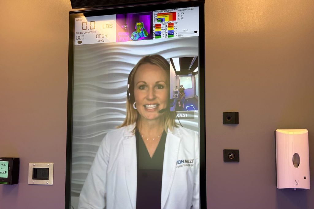Patients using OnMed booths are greeted by remote providers who appear on large, vertical video screens. (Arielle Zionts/KFF Health News)