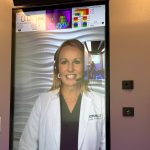 Patients using OnMed booths are greeted by remote providers who appear on large, vertical video screens. (Arielle Zionts/KFF Health News)