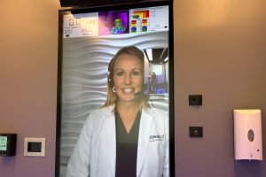 Patients using OnMed booths are greeted by remote providers who appear on large, vertical video screens. (Arielle Zionts/KFF Health News)