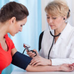 NP taking patient's blood pressure reading