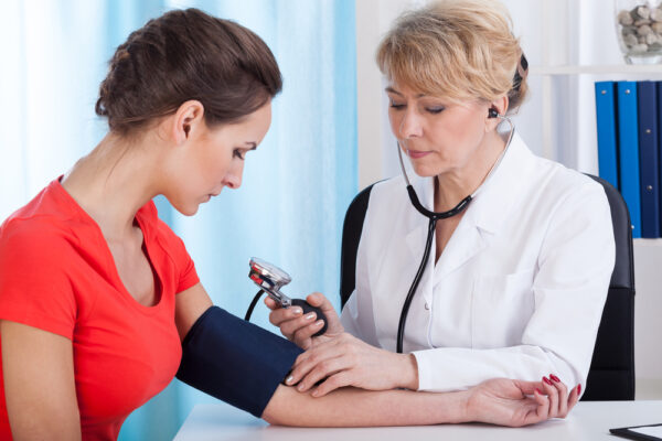NP taking patient's blood pressure reading